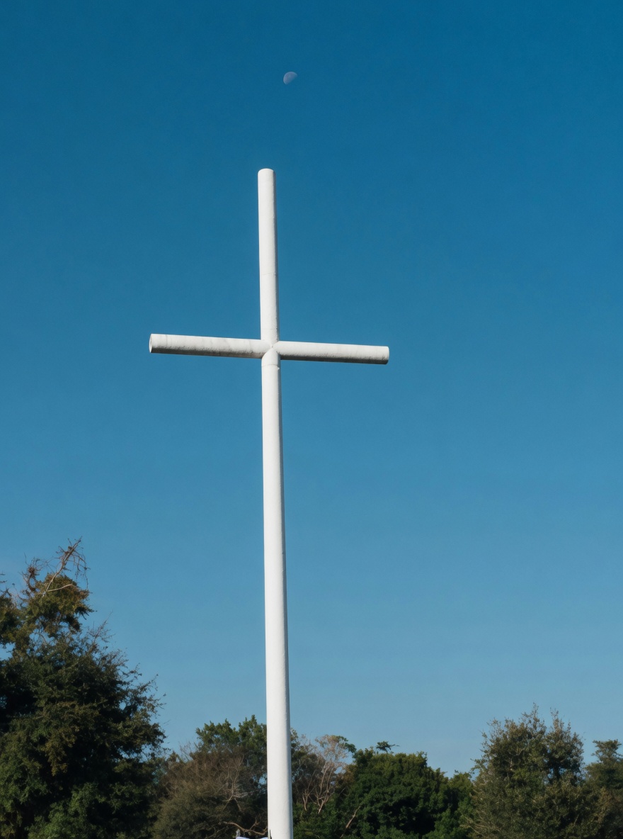 A white cross against a Florida sky on the church grounds.